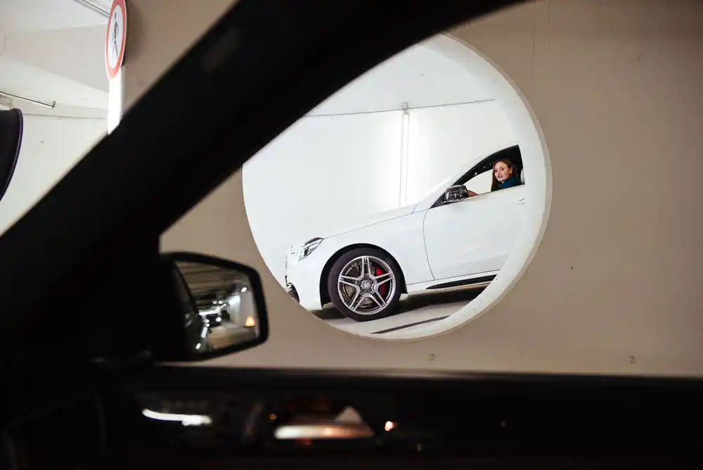 Weißes Auto, das in einer Parkgarage durch einen runden Durchgang fährt.
